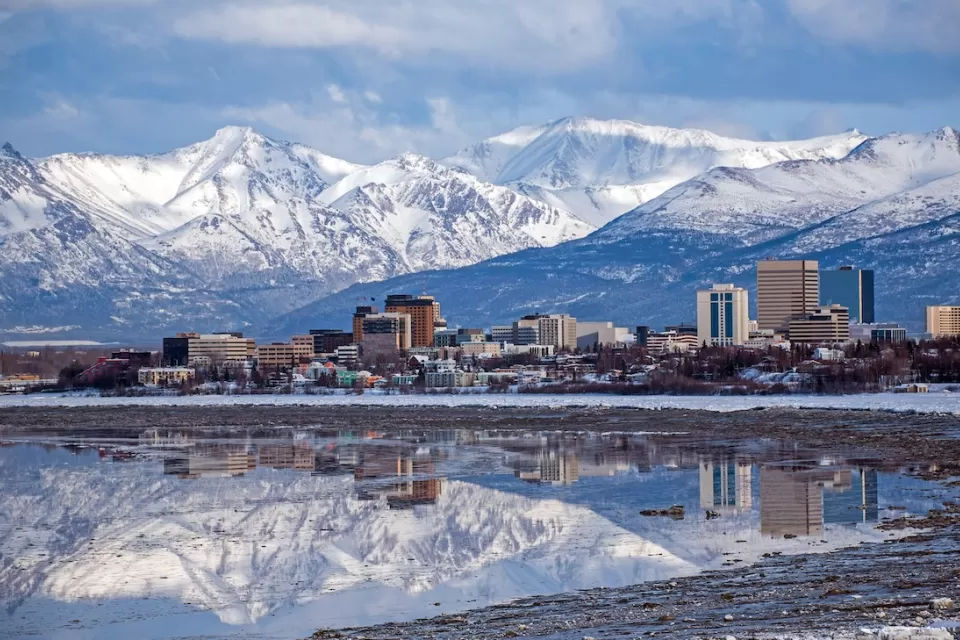 Anchorage, Alaska skyline with snowy mountains in background.